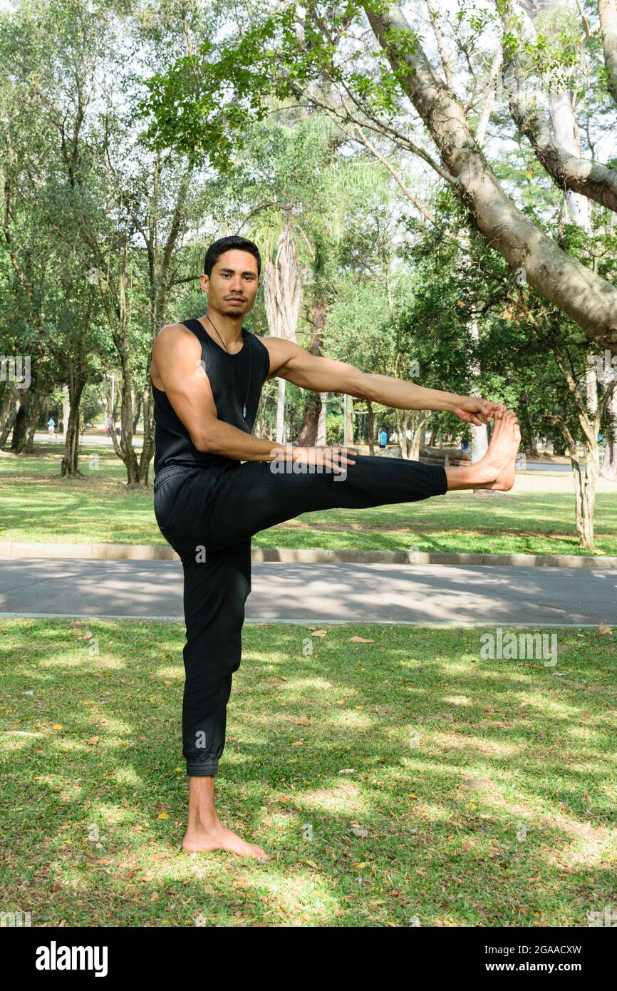 Jeune homme brésilien face à la caméra, en position équilibrée, dans un parc public par une journée ensoleillée. Banque D'Images