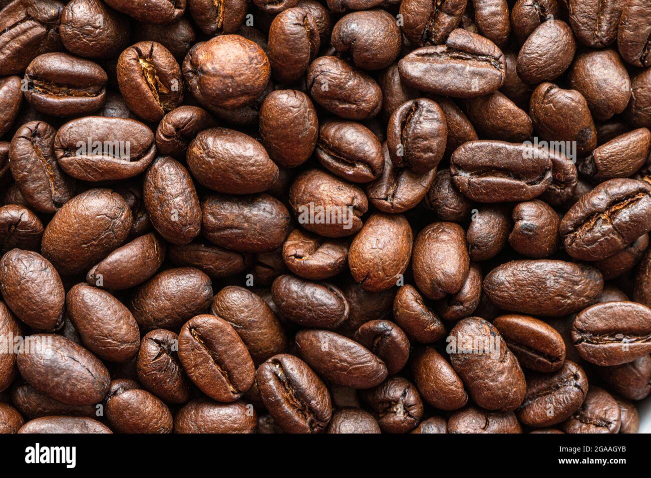 Fond de grains de café. Fond de grains de café torréfiés. Photo macro des grains de café frits sur la table. Banque D'Images