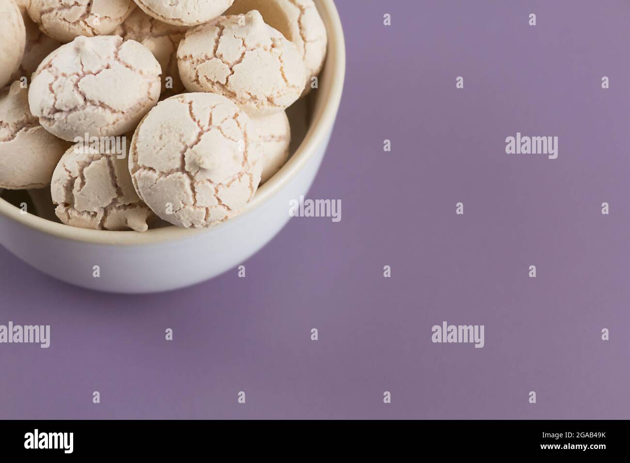 meringues dans un bol sur fond violet Banque D'Images