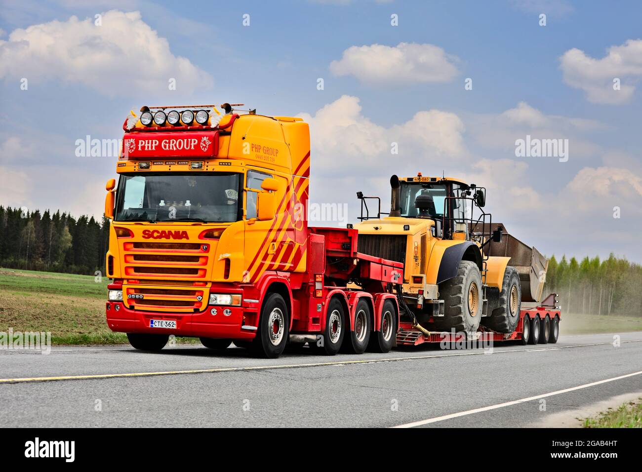 Le camion Scania G580 personnalisé du groupe PHP devant une remorque à col de cygne transporte la chargeuse sur pneus Cat sur la Highway 10. Tammela, Finlande. 14 mai 2021. Banque D'Images