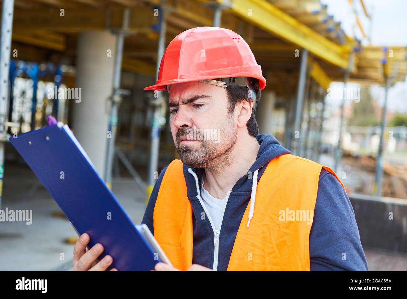 L'artisan ou le contremaître lit une liste de contrôle avec un rapport d'essai sur le chantier de construction de la maison Banque D'Images
