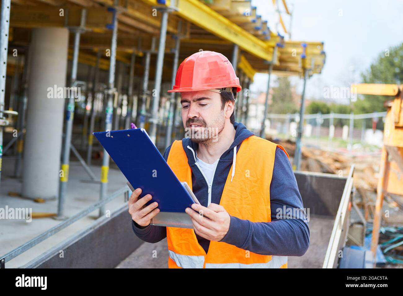 L'artisan ou le contremaître sur le chantier de construction de la maison lit le rapport d'essai sur le presse-papiers Banque D'Images