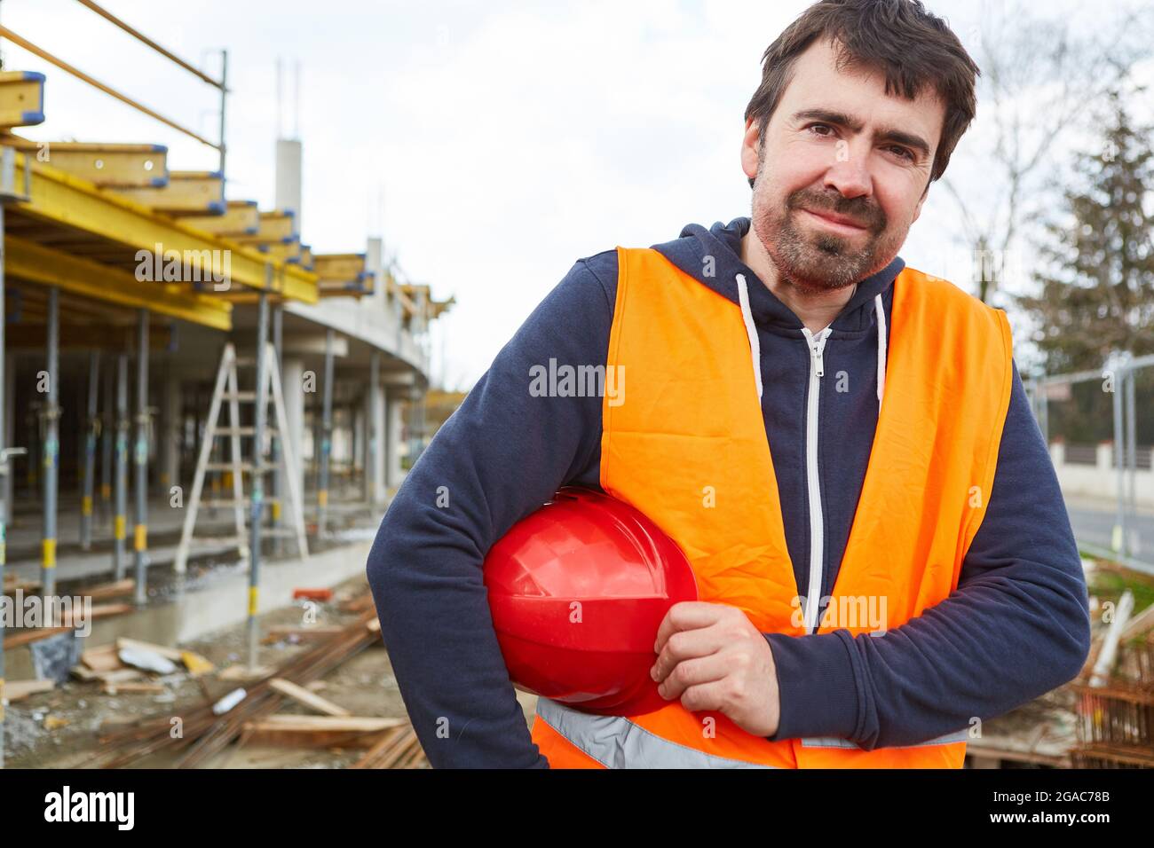 Artisan ou ouvrier de construction en vêtements de protection et avec casque sur le chantier de construction de la maison Banque D'Images