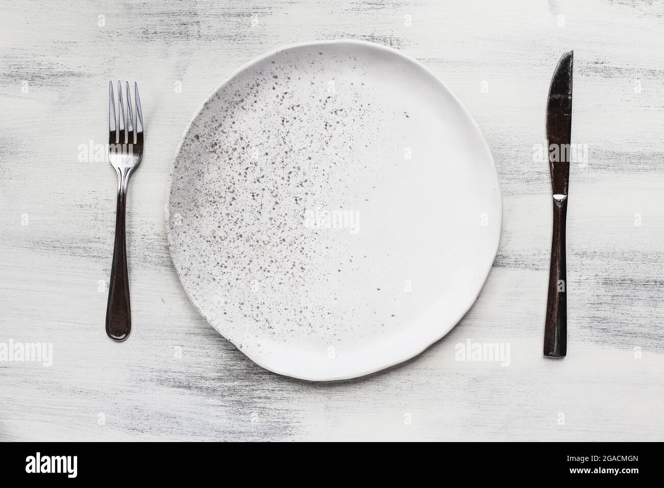 Plat d'une plaque à pois blanche avec des couverts sur une table en bois rustique. Banque D'Images