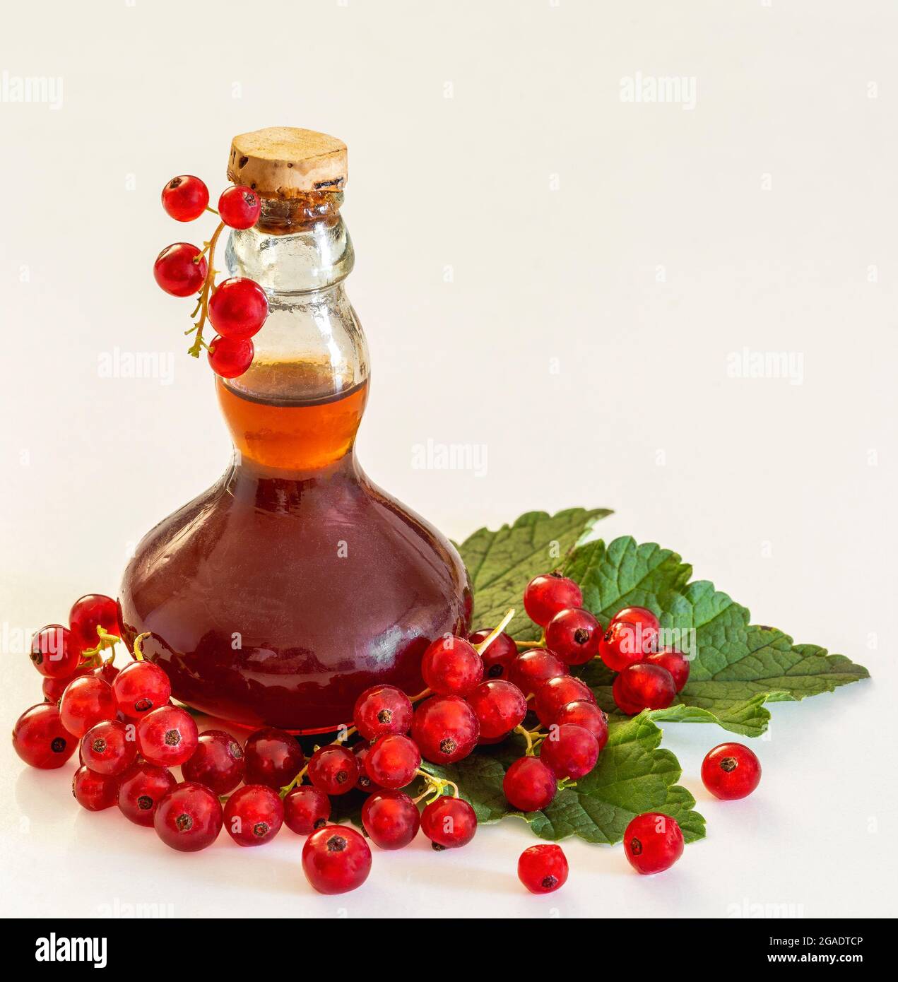 Raisins de Corinthe à côté d'une bouteille de brandy sur une feuille Banque D'Images