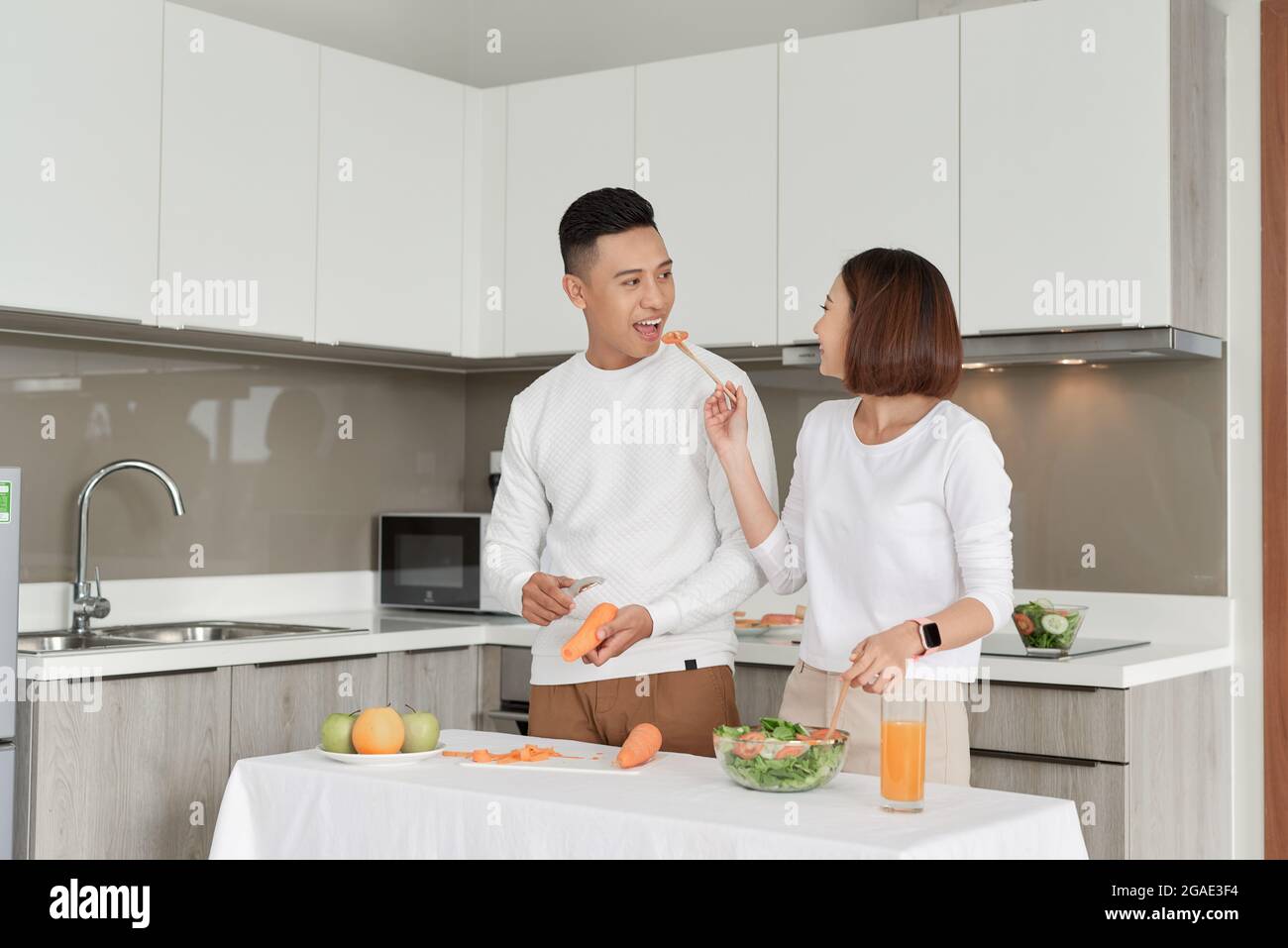 Heureux couple debout dans la cuisine à la maison préparant ensemble délicieux dîner sur la première datation Banque D'Images