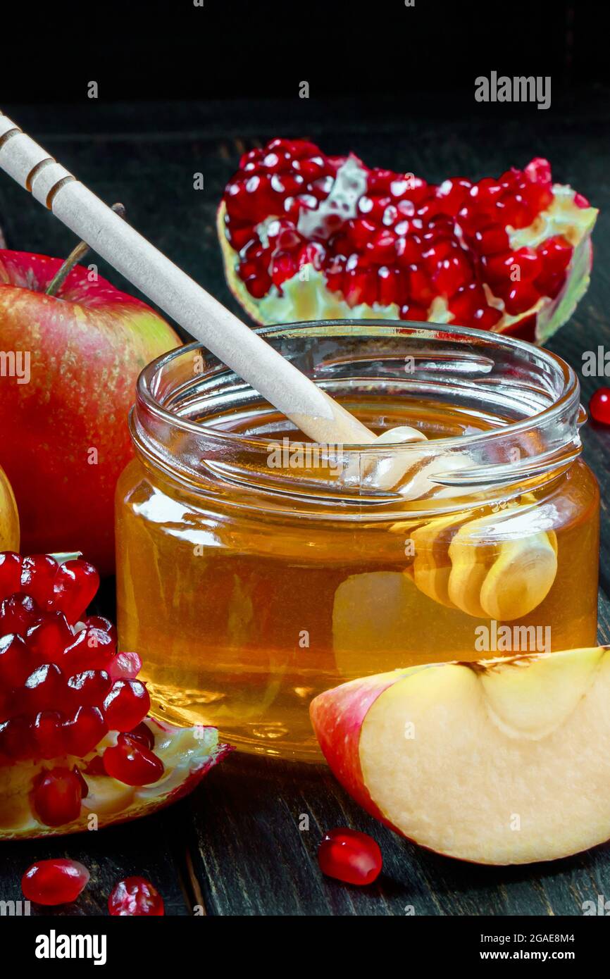 Fête religieuse juive traditionnelle Rosh Hashanah. Pommes, grenades et miel sur fond de bois foncé. Photo verticale. Banque D'Images