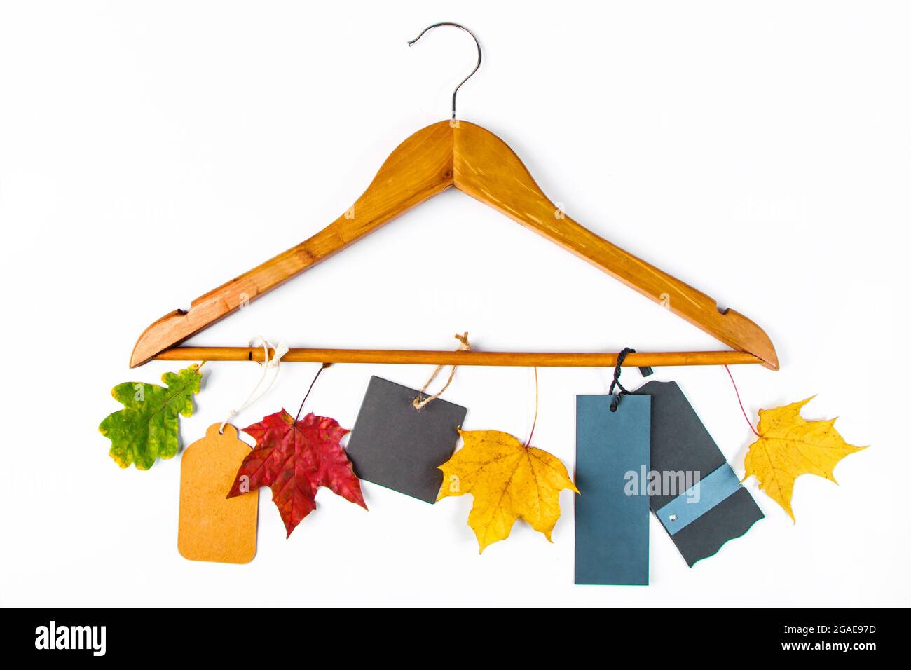 Soldes d'automne et remise. Porte-vêtements, feuilles jaunes et étiquettes vierges sur fond blanc. Concept de publicité. Banque D'Images