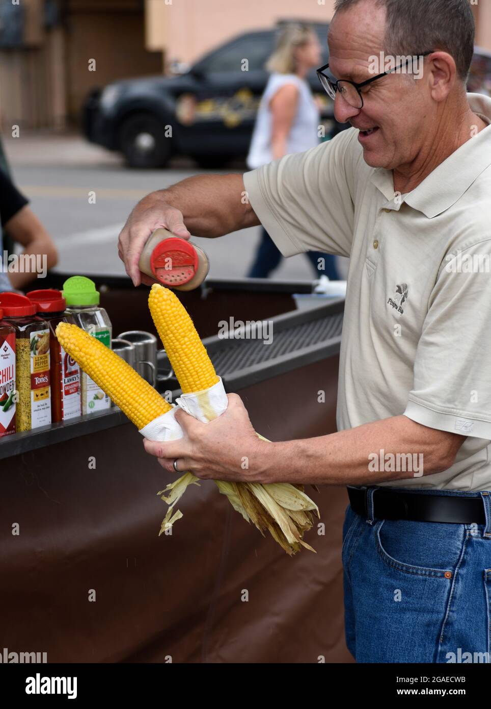 Un homme achète deux épis de maïs torréfié sur le rafle d'un stand de restauration lors d'un festival en plein air à Santa Fe, Nouveau-Mexique. Banque D'Images