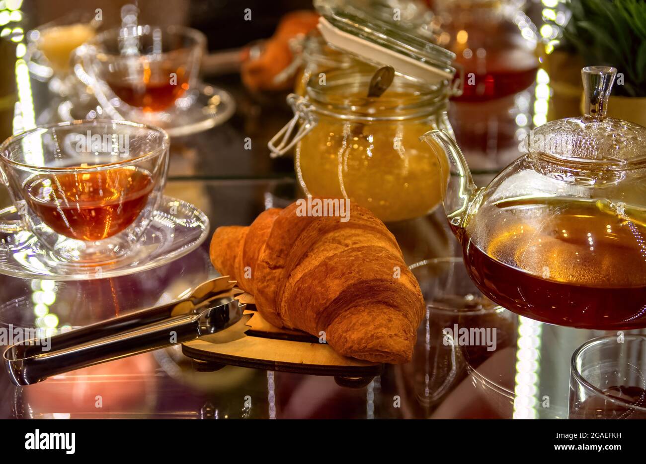 Croissant frais avec tasse de thé et confiture dans le café. Banque D'Images