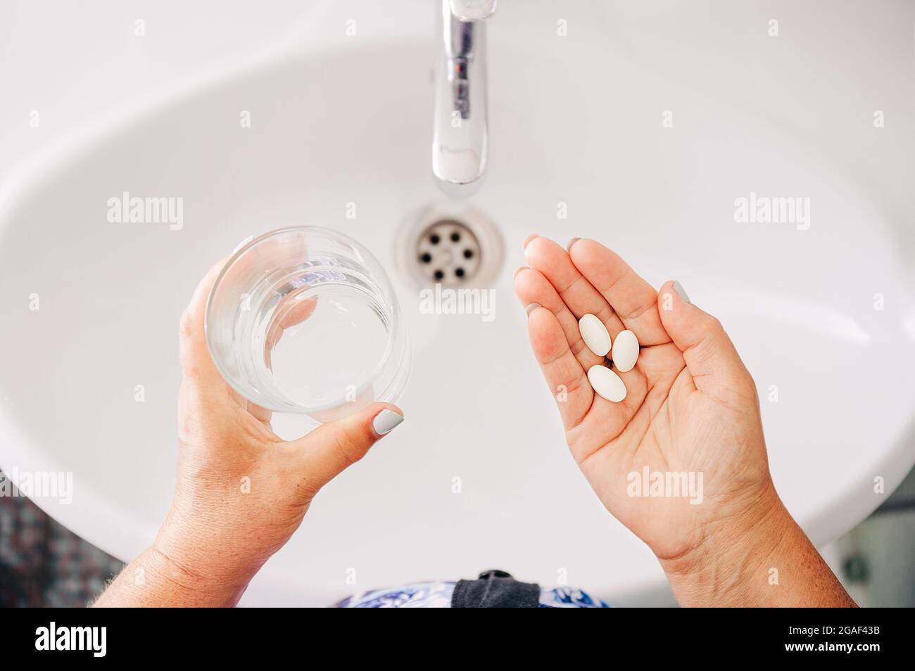 Femme senior prenant des pilules. Les femmes qui boivent des médicaments d'ordonnance, qui tiennent un verre d'eau. Traitement de la drogue. Vue de dessus des mains Banque D'Images