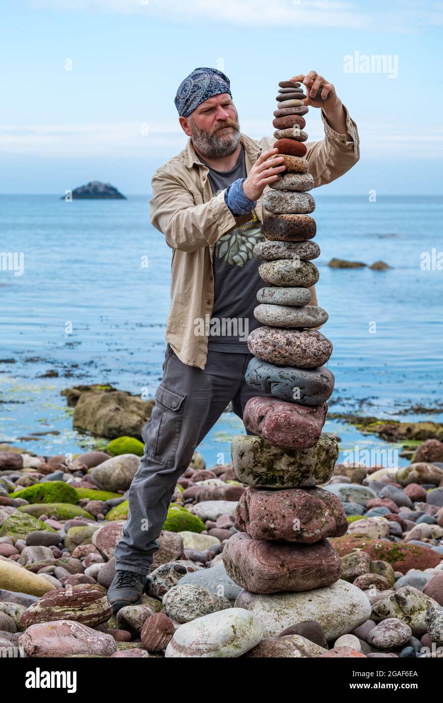 James Brunt, artiste terrestre, empile des pierres dans une tour du championnat européen de pierre sur la plage, Dunbar, East Lothian, Écosse, Royaume-Uni Banque D'Images