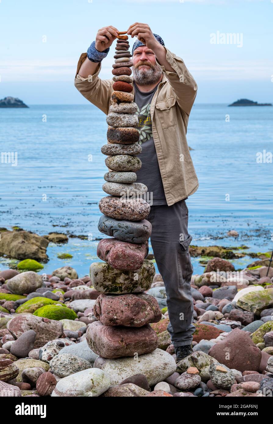 James Brunt, artiste terrestre, empile des pierres dans une tour du championnat européen de pierre sur la plage, Dunbar, East Lothian, Écosse, Royaume-Uni Banque D'Images