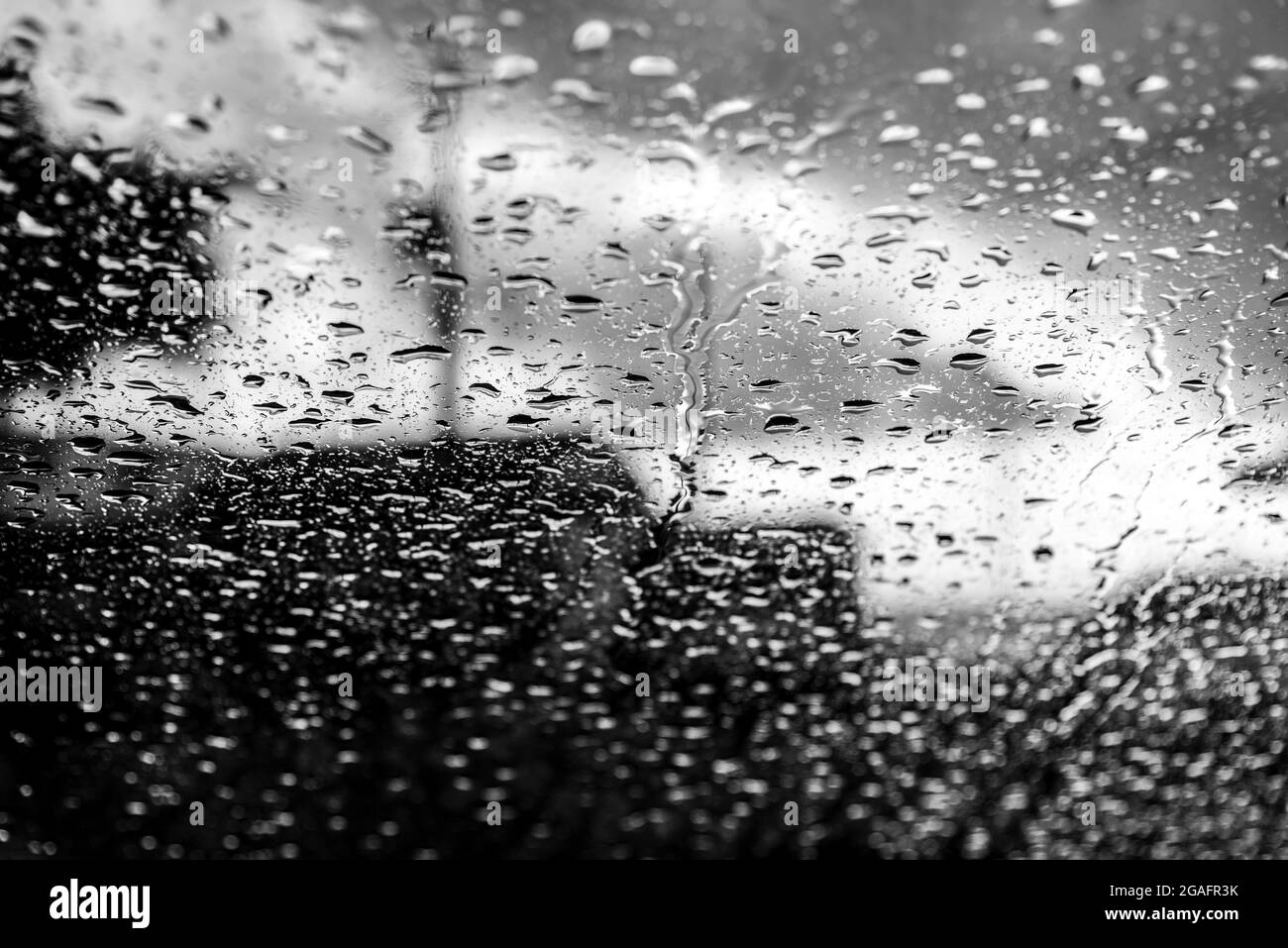 Bokeh, chuva, gotas de água pelo vidro do carro. Dia chuvoso. Lanternes de carros desfocadas. Colorido. Banque D'Images