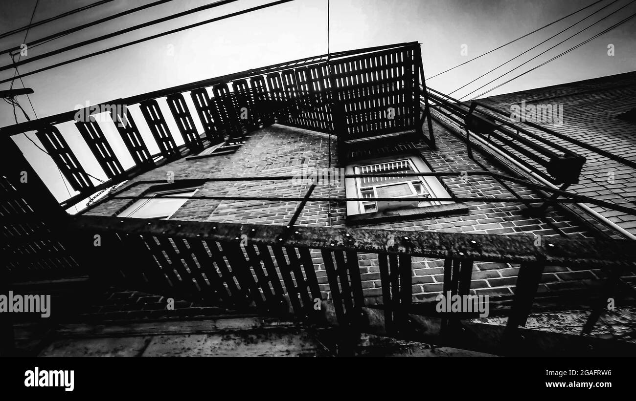 Photo en bas angle de l'escalier de sortie d'incendie d'un ancien bâtiment en niveaux de gris Banque D'Images