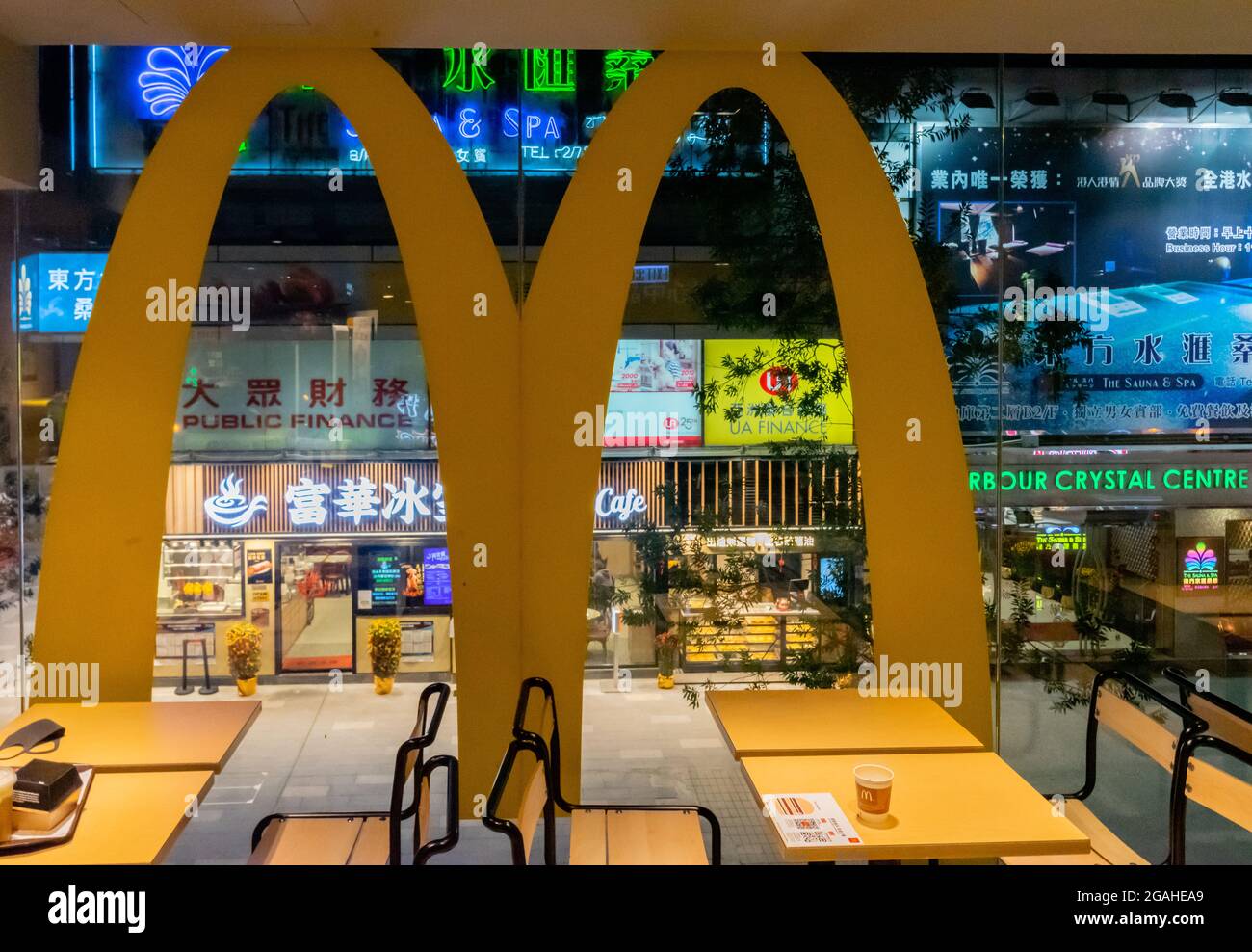 Une vue sur les restaurants et les centres de spa avec des enseignes au néon dans la nuit à travers la fenêtre avec "M" du restaurant McDonald's, Tsim Sha Tsui, Hong Kong, Chine Banque D'Images