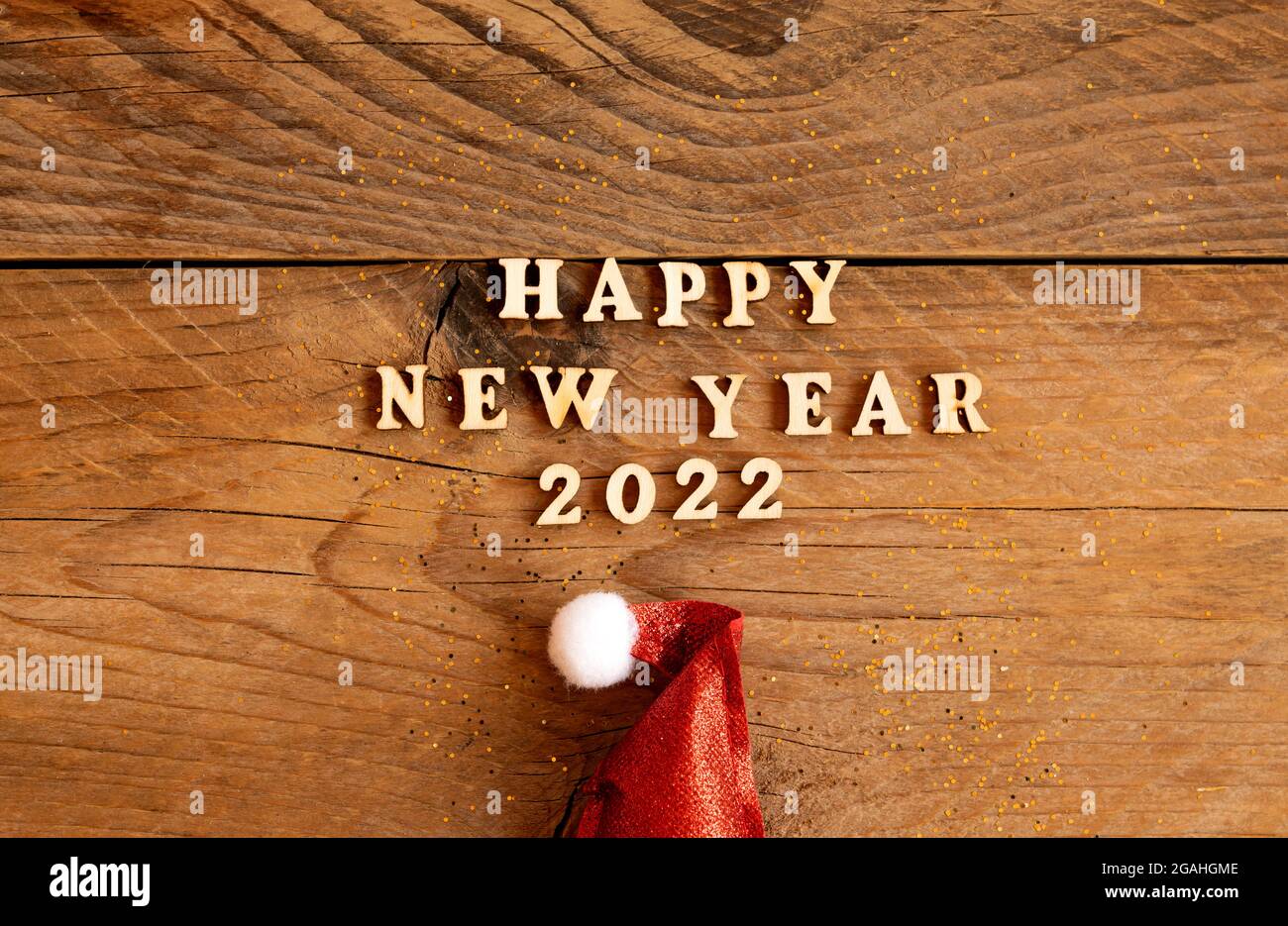 Bonne Annee 22 Lettres En Bois Citation Avec Chapeau De Pere Noel Rouge Etincelant Sur Table En Bois Avec Paillettes Carte De Vœux Festive Pour Une Fete Du Nouvel An Photo Stock
