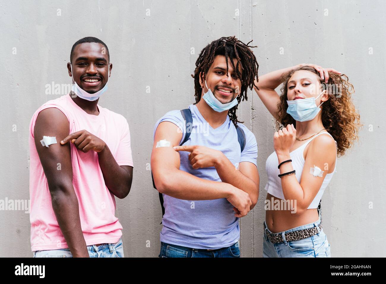 amis africains, latino-américains et caucasiens montrant des armes. Concept du programme de vaccination Covid Banque D'Images