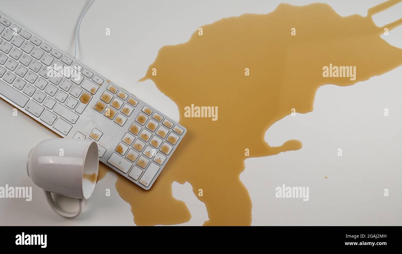 Tasse de café noir renversée sur le clavier de l'ordinateur sur la table blanche. Banque D'Images Tasse de café noir renversée sur le clavier de l'ordinateur sur la table blanche. Banque D'Images