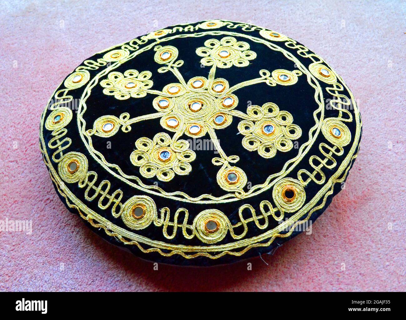 Coussin rond de style indien avec tresse et miroirs sur une moquette rose Banque D'Images