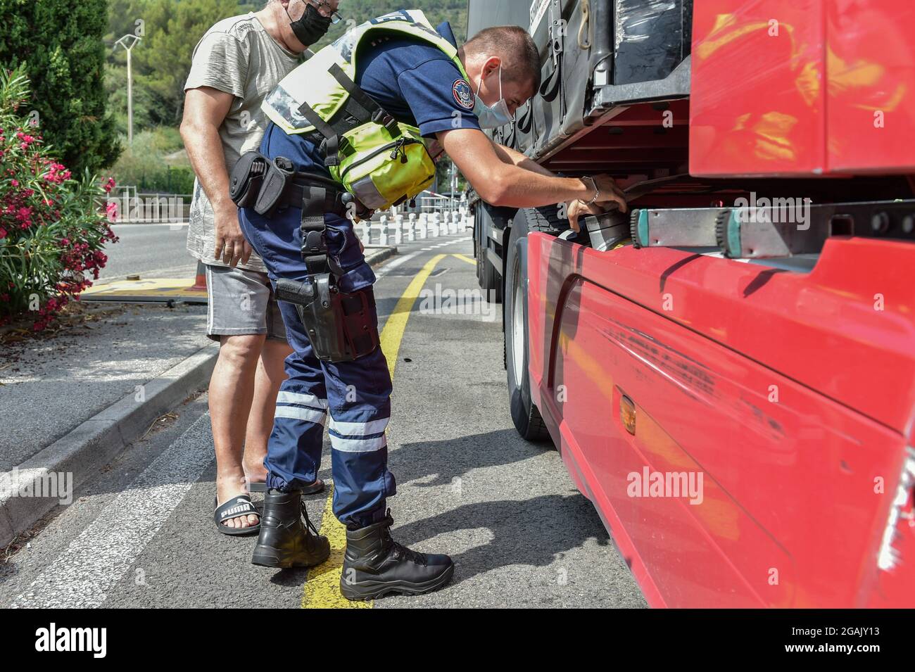 Nice, France. 26 juillet 2021. Un agent des douanes prélève des échantillons de carburant dans un camion à la frontière avec l'Italie sur l'autoroute la Turbie. Le prochain renforcement des mesures de lutte contre l'épidémie de coronavirus en France et l'installation de la passe sanitaire amène le gouvernement à renforcer les contrôles aux frontières. En plus des contrôles habituels, les agents des douanes et la police aérienne et frontalière vérifient la validité de la carte sanitaire et des tests PCR que les voyageurs présentent à leur arrivée. Crédit : SOPA Images Limited/Alamy Live News Banque D'Images