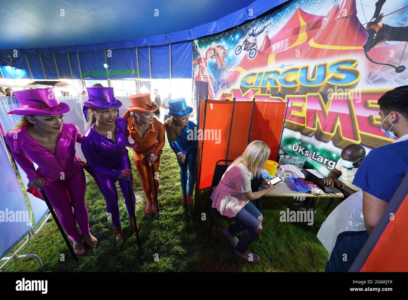 Les artistes de Circus Extreme regardent Rhiannon Alexander, 34 ans, de Bradford, attendre une vaccination Covid-19 dans une clinique de vaccination pop-up dans le chapiteau du cirque de Halifax. Date de la photo: Samedi 31 juillet 2021. Banque D'Images