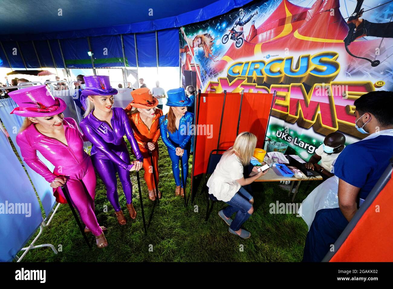 Les artistes de Circus Extreme regardent Rhiannon Alexander, 34 ans, de Bradford, attendre une vaccination Covid-19 dans une clinique de vaccination pop-up dans le chapiteau du cirque de Halifax. Date de la photo: Samedi 31 juillet 2021. Banque D'Images