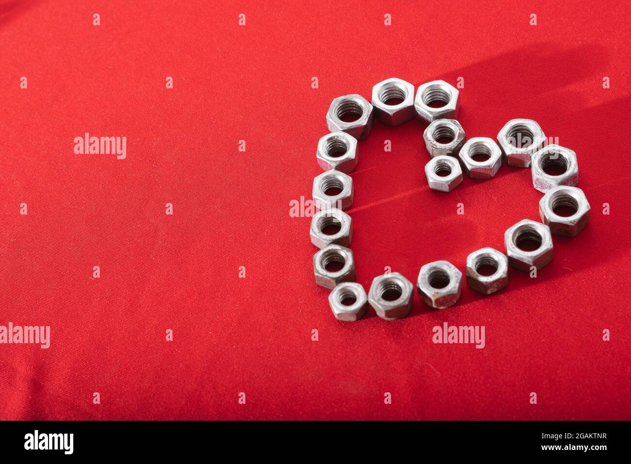 Coeur fait de noix d'acier sur fond rouge, concept de l'amour, la paix et la bonté, laissant de l'espace pour le texte publicitaire Banque D'Images
