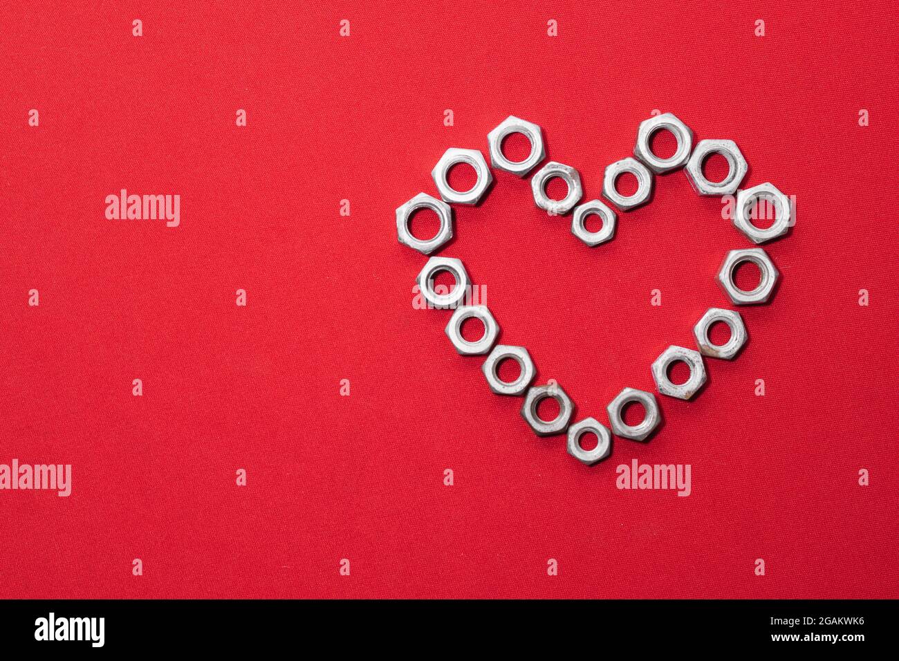 Coeur fait de noix d'acier sur fond rouge, concept de l'amour, la paix et la bonté, laissant de l'espace pour le texte publicitaire Banque D'Images