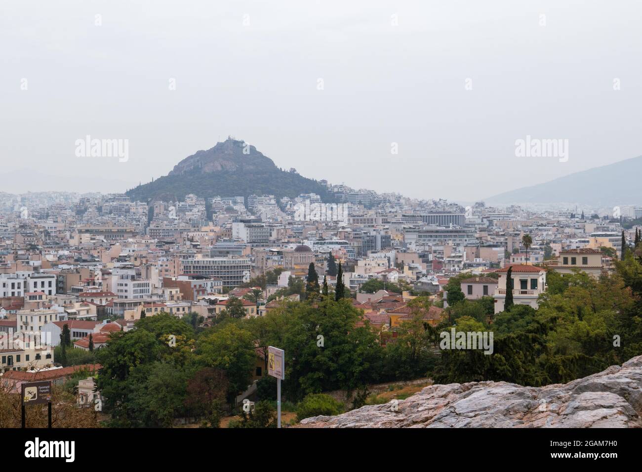 Vue sur le mont Lycabette et le centre de la vieille ville d'Athènes avec la verdure d'été en journée de brouillard gris depuis Areopagus - colline près de l'Acropole Banque D'Images