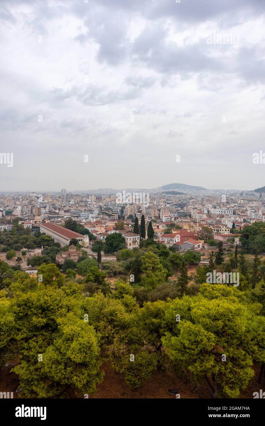 STOA d'Attalos Église des Saints Apôtres dans la verdure et le centre-ville d'Athènes avec des nuages dramatiques d'Areopagus - colline près de l'Acropole. Verticale Banque D'Images