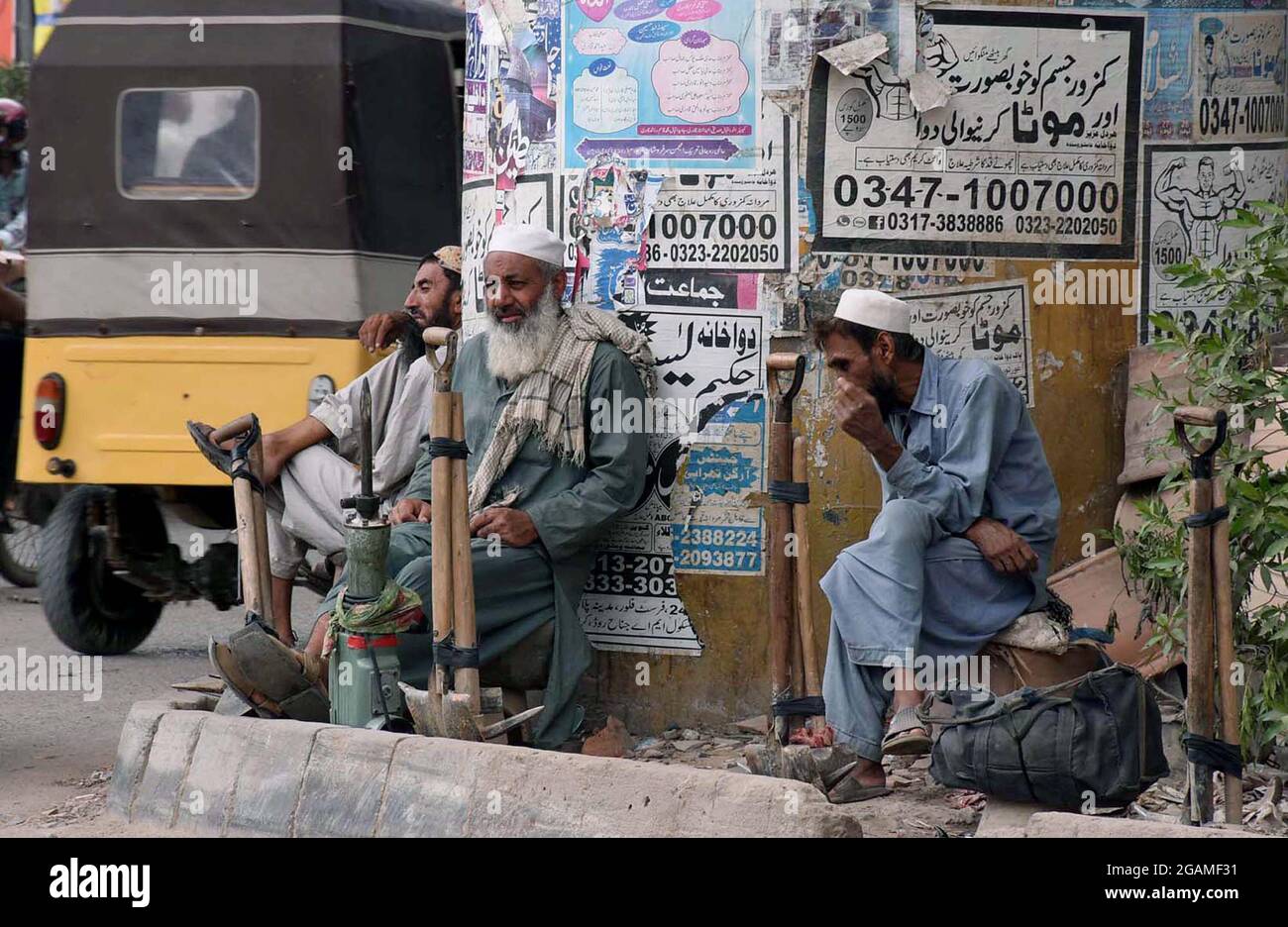 Les travailleurs sans emploi sont assis sur le bord de la route pendant qu'ils attendent leur emploi lors d'un verrouillage intelligent complet imposé par le gouvernement provincial en raison de l'augmentation des cas de coronavirus, comme mesure préventive contre la propagation du coronavirus (COVID-19), à Karachi le samedi 31 juillet 2021. Les autorités provinciales ont imposé un verrouillage partiel dans la province du sud du Sindh au Pakistan, y compris le centre commercial de Karachi et d'autres centres urbains, en raison d'une augmentation alarmante des cas de COVID-19. Banque D'Images