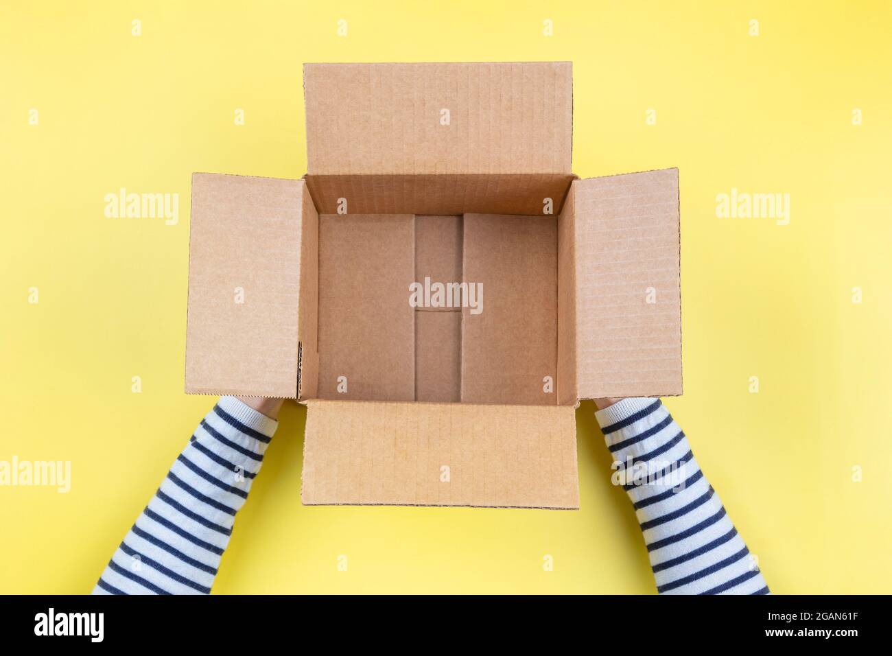 Mains De Femmes Avec Une Boite En Carton Vide Ouverte Sur Fond Jaune Pastel Vue De Dessus Photo Stock Alamy