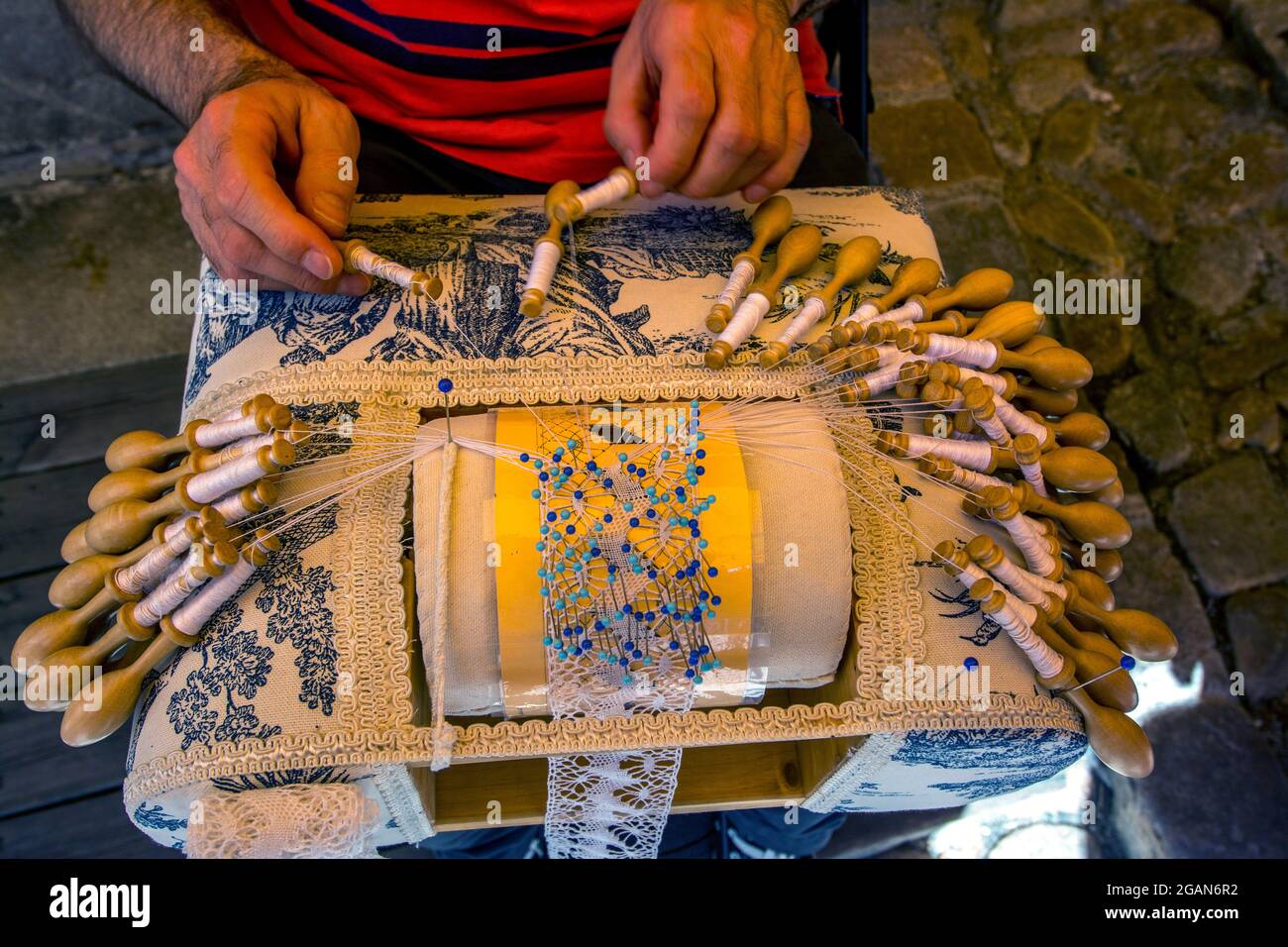 Homme faisant de la dentelle française traditionnelle avant son magasin. Le Puy-en-Velay, Auvergne-Rhône-Alpes, France. Banque D'Images
