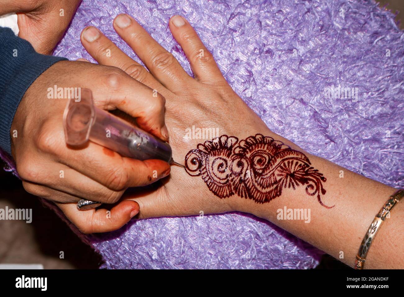 Henné artiste appliquant le henné sur la main. Banque D'Images