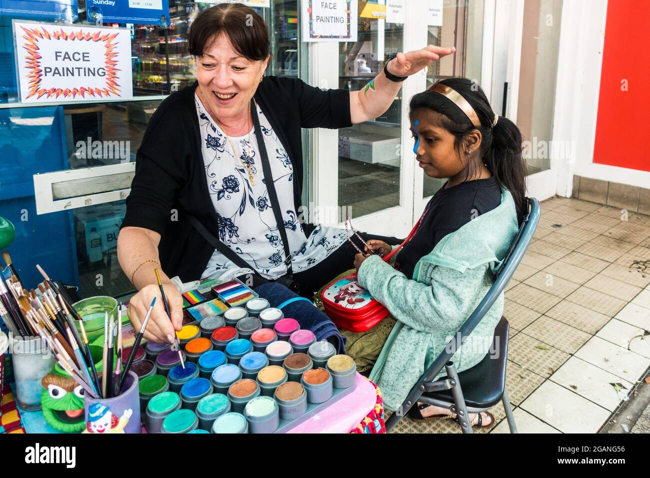 Peinture de visage sur enfant par des artistes à l'extérieur d'un magasin WHSmith dans la rue haute de Croydon Banque D'Images