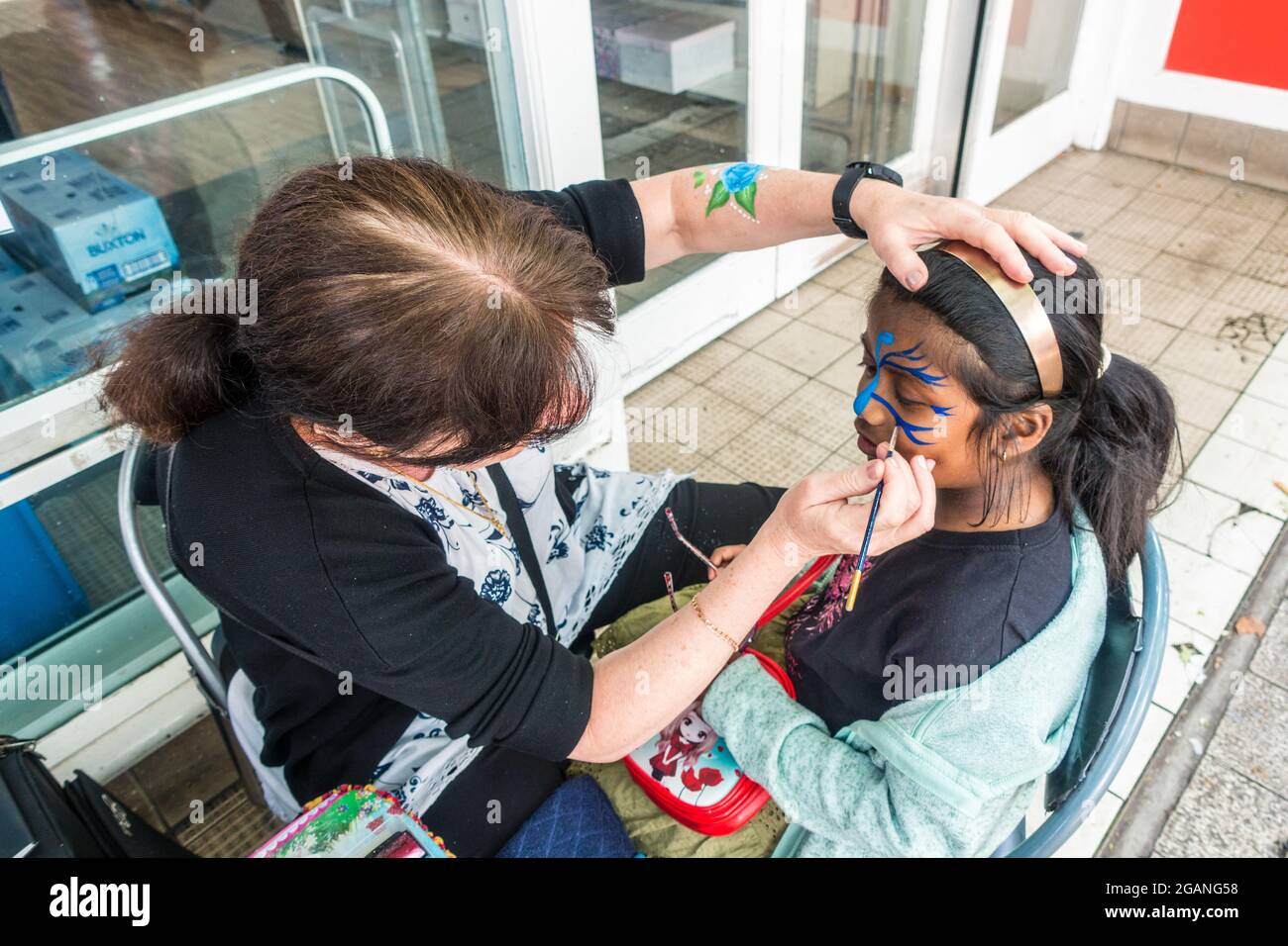 Visage peinture enfant par artiste sur la rue haute en Angleterre Banque D'Images