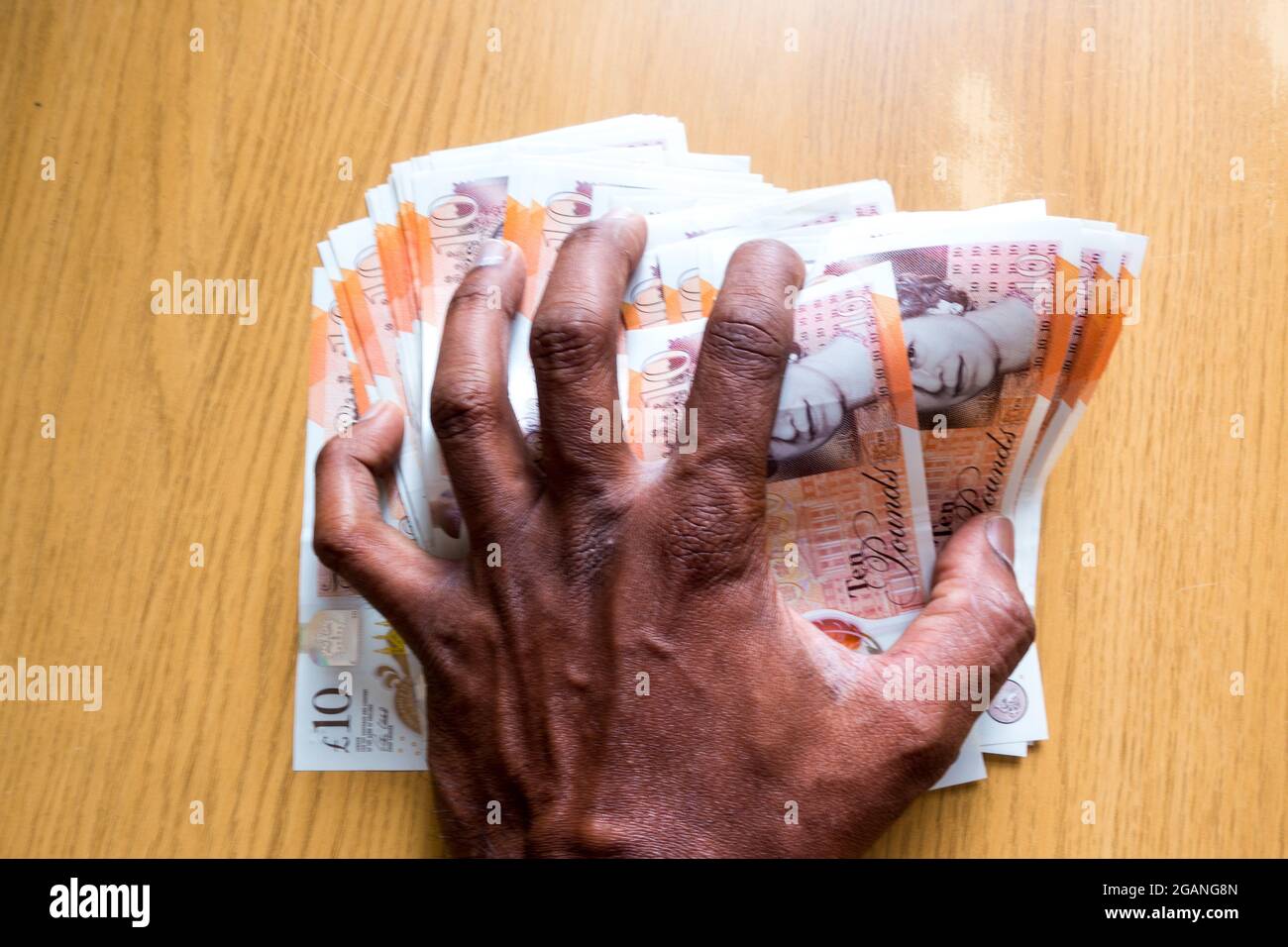 Homme d'âge moyen indien asiatique écrasant des notes de currenty anglais avec la main Banque D'Images