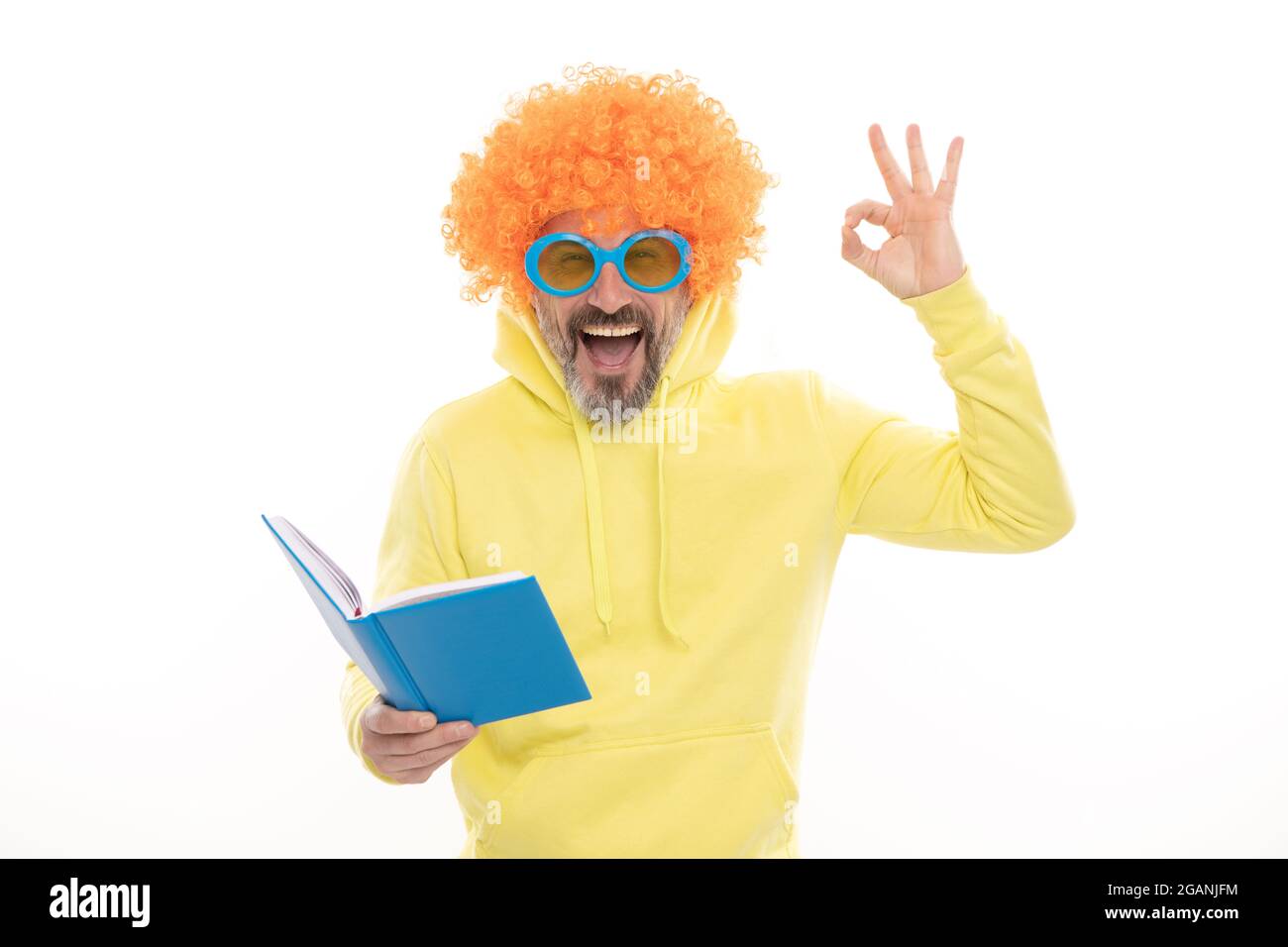 Happy man dans funky perruque show OK signe gestuel lecture livre d'école dans geek lunettes de soleil, éducation Banque D'Images