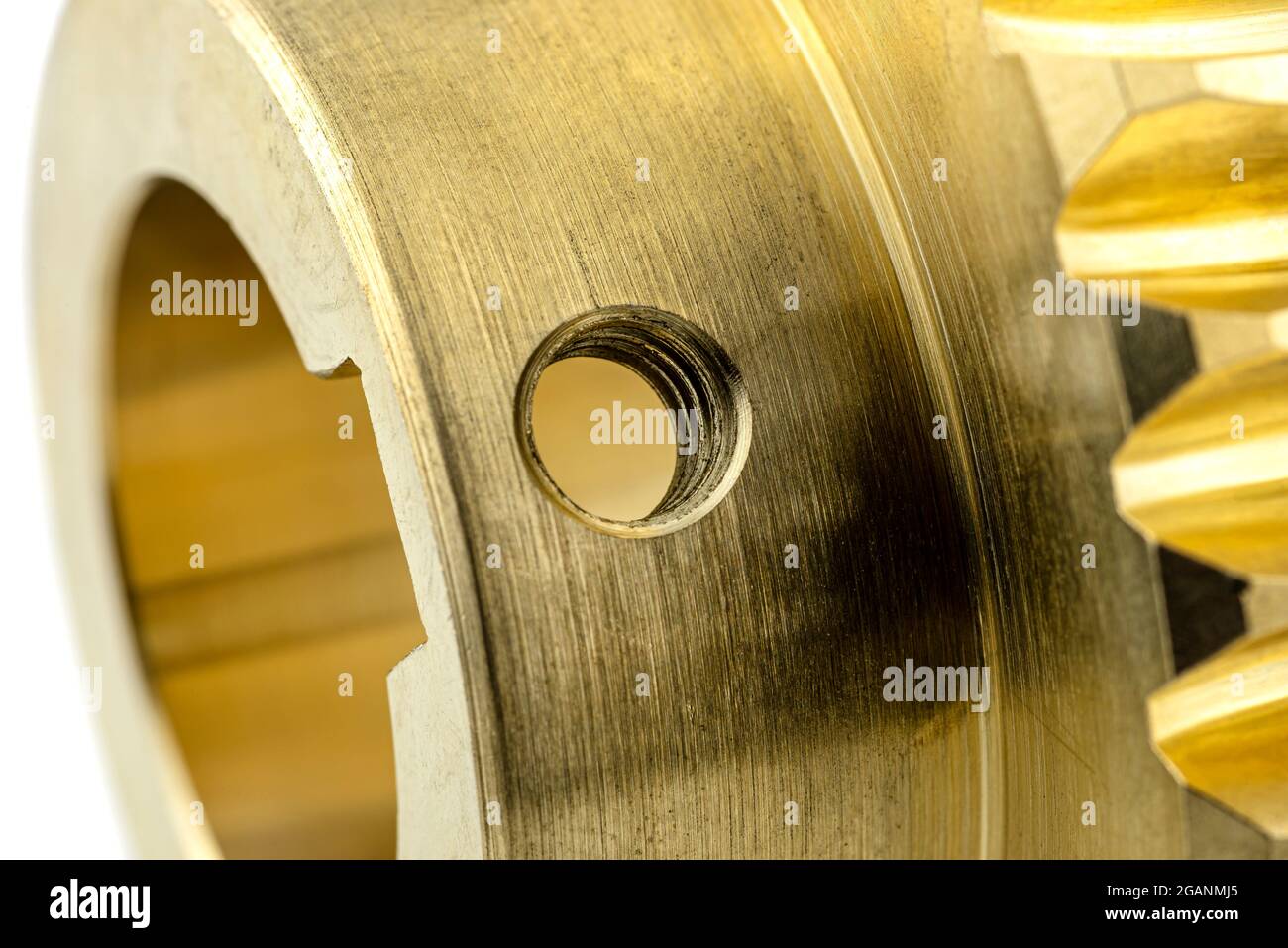 Photo macro d'un nouvel engrenage en cuivre brillant, isolé sur fond blanc, trou visible pour la vis de blocage. Banque D'Images