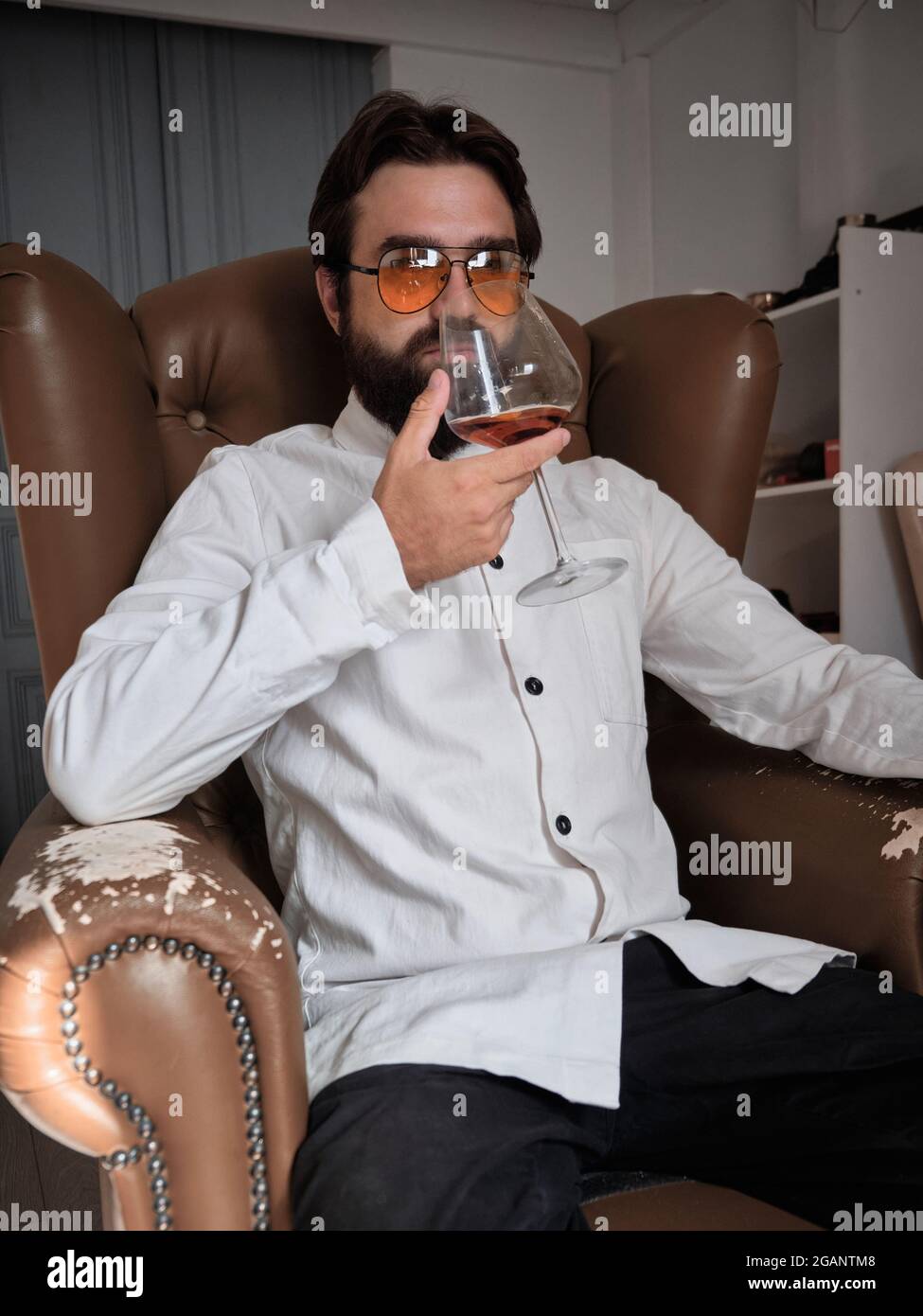 L'homme est assis dans un fauteuil avec un verre de liqueur Banque D'Images