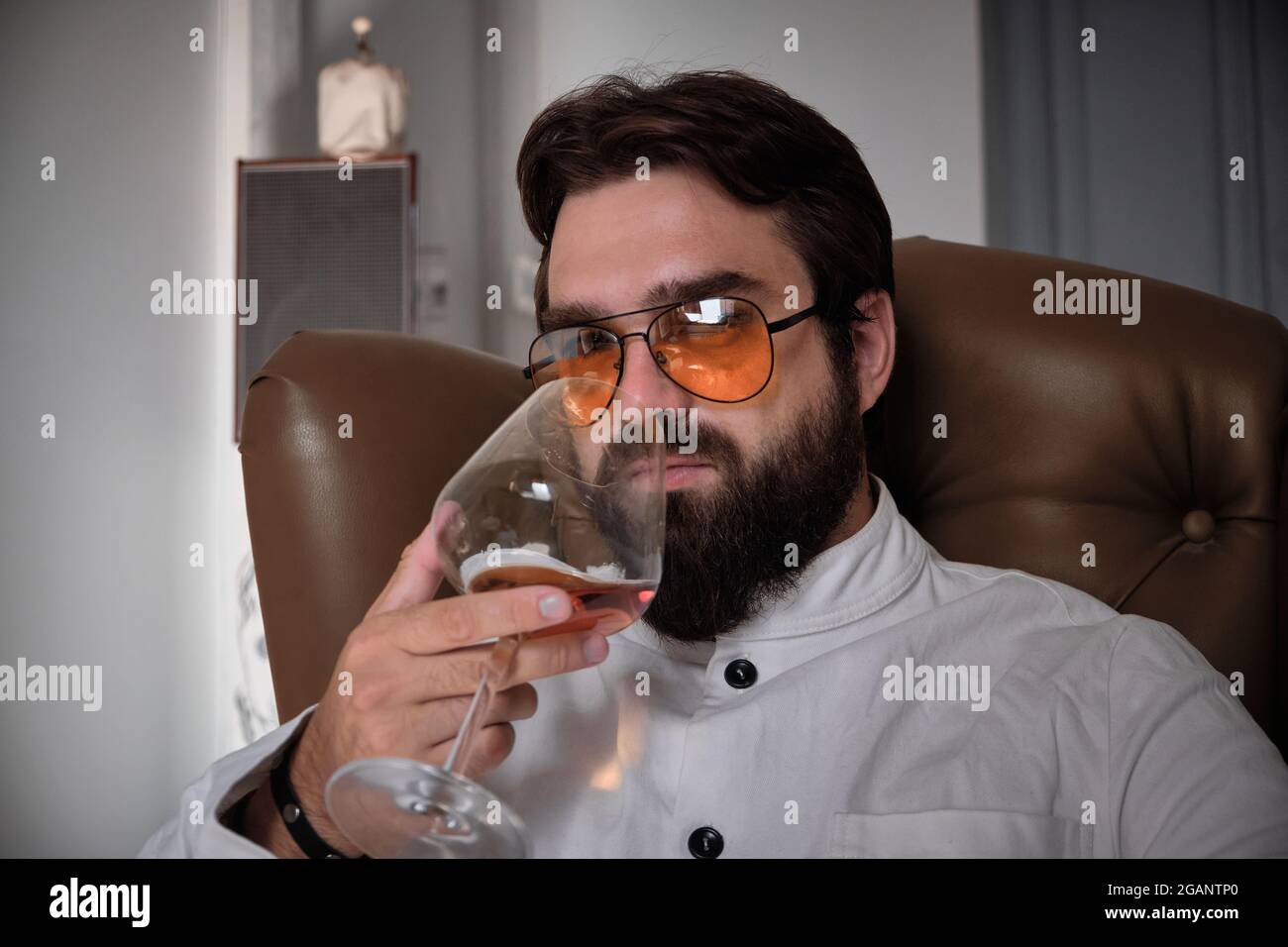 L'homme est assis dans un fauteuil avec un verre de liqueur Banque D'Images