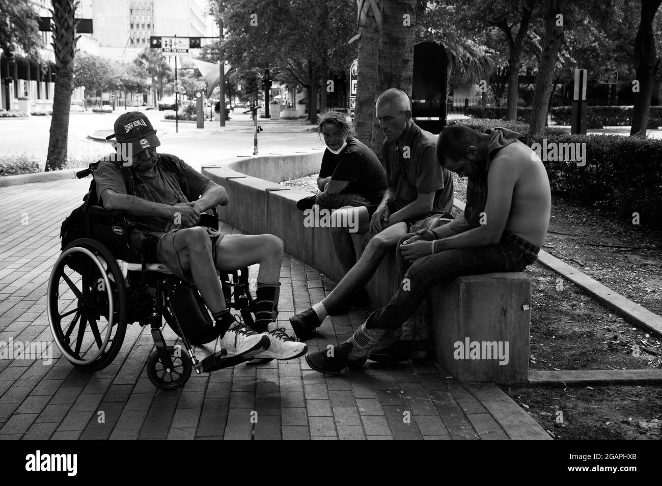 Tampa, Floride, États-Unis. 31 juillet 2021. Les hommes et les femmes sans domicile passent le temps à l'ombre des arbres le long d'une rue du centre-ville de Tampa. Les quelques refuges de la ville sont remplis à pleine capacité, ont déclaré les défenseurs. « nous avons beaucoup de sans-abri qui comer ici avec un billet de bus aller simple depuis d'autres villes », a noté un policier local. « tous ceux qui dorment dans la rue ont des problèmes de maladie mentale », a-t-il déclaré. (Image de crédit : © Robin Rayne/ZUMA Press Wire) Banque D'Images