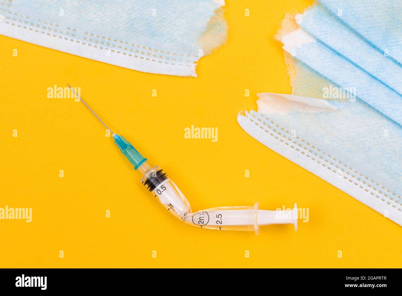 Anti-mouvement de vaccin et anti-masque concept - seringue médicale cassée et masque médical déchiré se trouvant sur fond jaune. Pandémie et verrouillage - vue de dessus, plat Banque D'Images