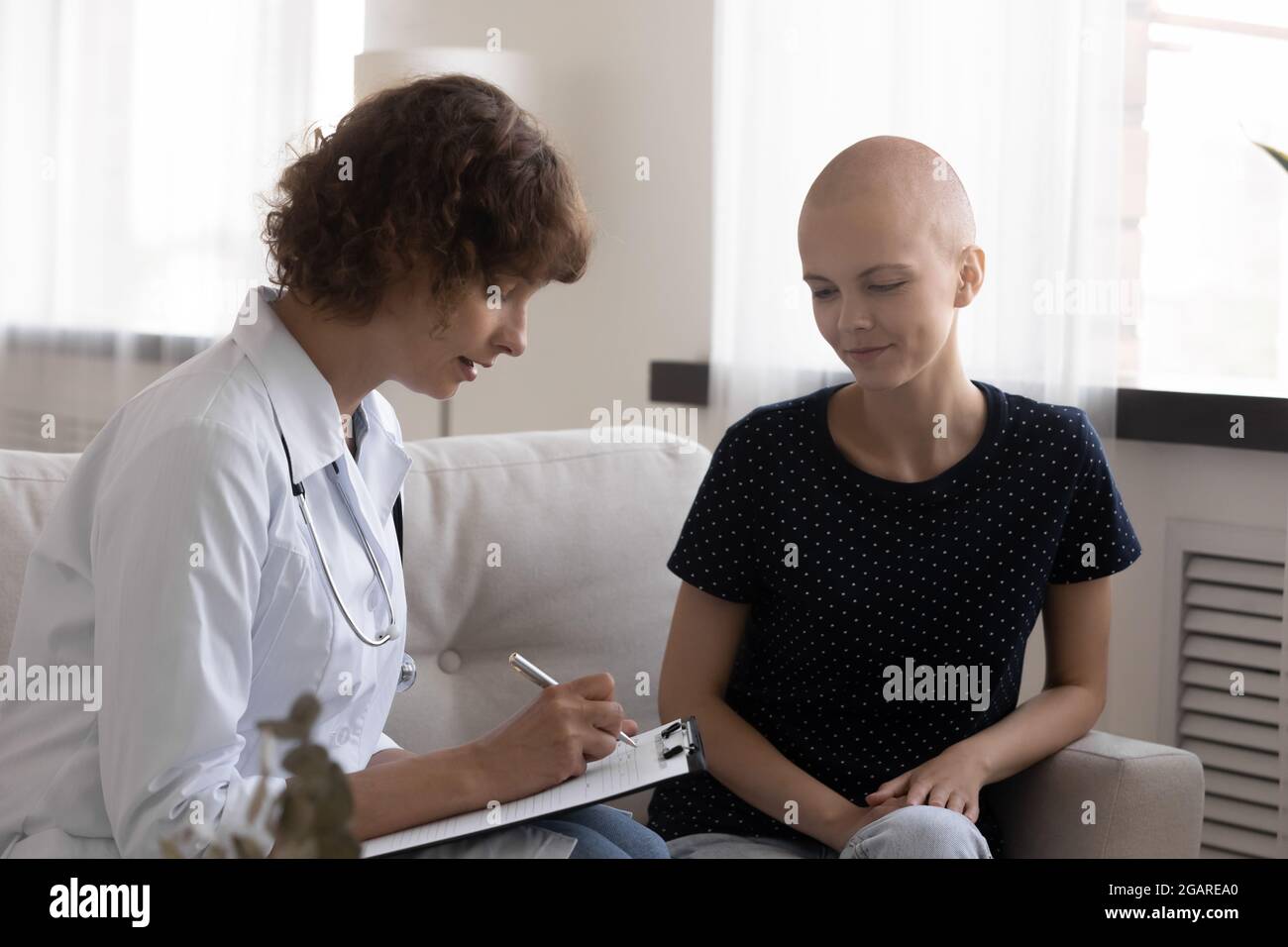 Jeune oncologue concentré prescription d'écriture à un patient cancéreux. Banque D'Images