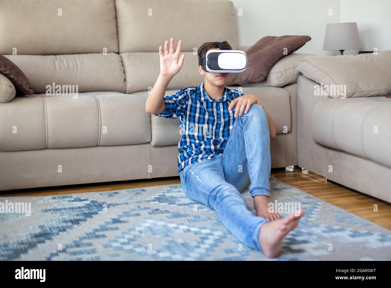Adolescent de race blanche portant des lunettes de réalité virtuelle, jouant et essayant de toucher quelque chose avec sa main. Banque D'Images