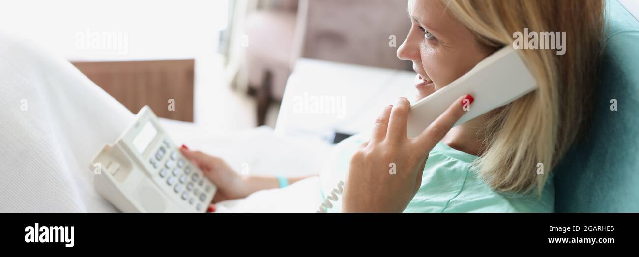 Femme souriante parlant au téléphone tout en étant allongé dans la chambre d'hôtel Banque D'Images