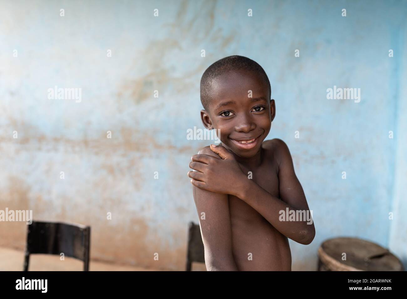 Après avoir été vacciné contre le tétanos, un petit enfant africain souriant couvre son bras supérieur où un grand plâtre a été appliqué Banque D'Images