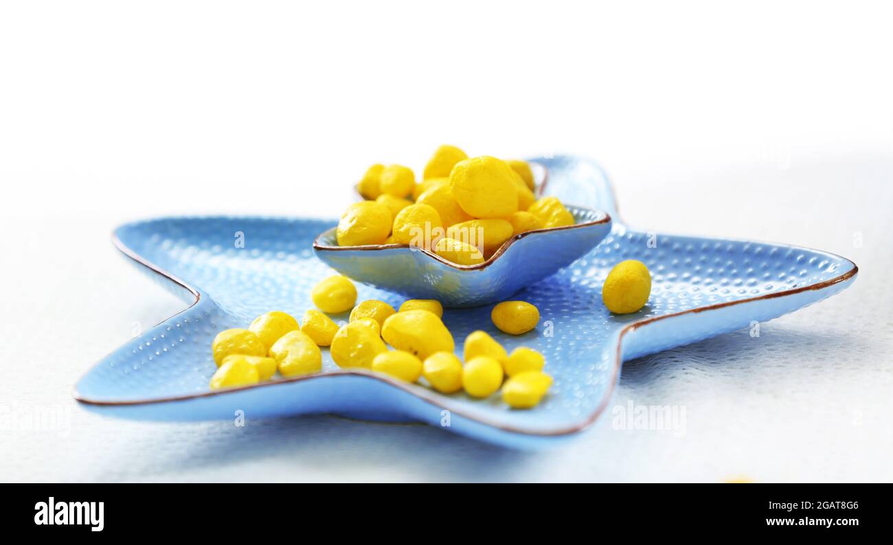 Bonbons jaunes dans un bol en forme d'étoile bleu sur la table Banque D'Images
