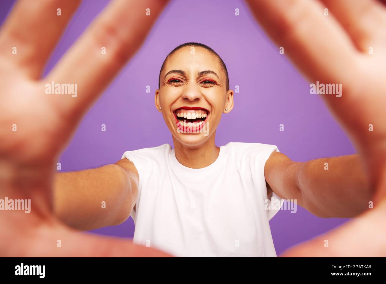 Portrait d'une femme gaie avec les mains devant. Femme avec la tête rasée regardant l'appareil photo et souriant. Banque D'Images